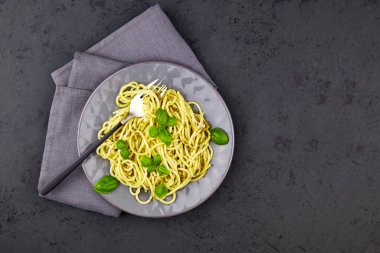 Pesto soslu makarna, parmesan ve koyu gri arka planda fesleğen. Üst görünüm, alanı kopyala
