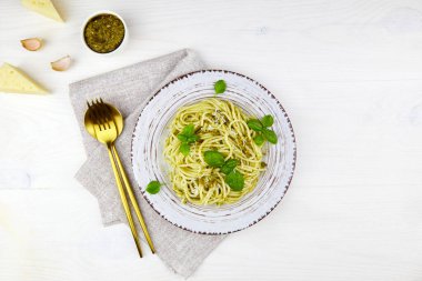 Beyaz ahşap arka planda bir tabakta pesto, parmesan ve fesleğen ile makarna. Üst görünüm, boşluğu kopyala. Yüksek kalite fotoğraf