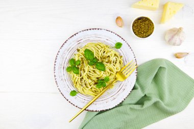 Beyaz ahşap arka planda bir tabakta soslu, parmesanlı ve fesleğenli İtalyan makarna. Üst görünüm, boşluğu kopyala. Yüksek kalite fotoğraf