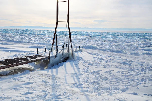 Eisiger Pier, eine Vorrichtung, um ein Boot in den See zu bringen. Zugefrorener Baikalsee, Buckelpisten — Stockfoto