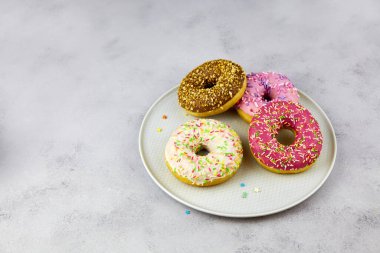 Gri arkaplanda tabakta renkli çörekler.