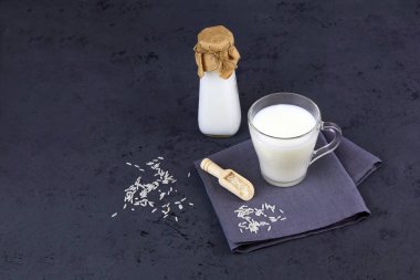 Cam bardakta pirinç sütü ve koyu gri arka planda bir şişe. Vejetaryen laktozsuz. Sebze sütü. Boşluğu kopyala. 