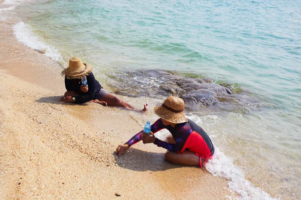 Дві жінки збирають мушлі, краби та інші морепродукти на березі моря . — стокове фото