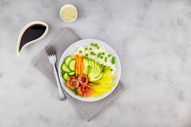 Somon, pirinç, avokado, salatalık, mango, mikro yeşil, yeşil bezelye ve gri zemin üzerinde havuç.. 