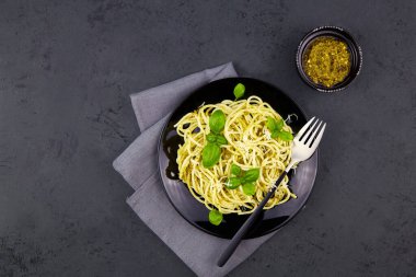 Pesto soslu makarna, parmesan ve koyu gri arka planda fesleğen. Üst görünüm