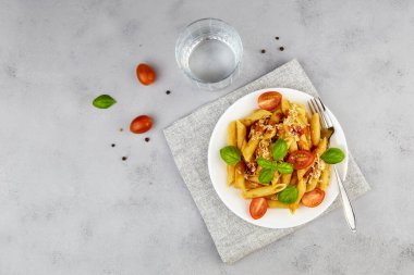 Domatesli İtalyan makarna makarna, gri arka planda peynir ve fesleğen. Üst görünüm 