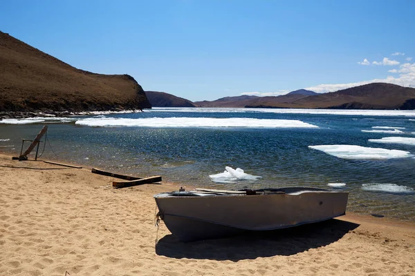 Boat on the sandy shore of Lake Baikal on a sunny spring day. Ice drift. — Stock Photo, Image