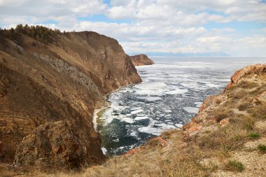 View to the north of Olkhon Island, Cape Khoboy. Lake Baikal in the spring. White ice floes melt on the water