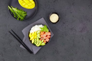 Hawaii ahi, somon, pilav, avokado, salatalık, mango, siyah arka planda otlar.. 