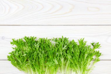 Beyaz ahşap arka planda çiğ organik yeşil friz salatası. Kapatın. Üst Manzara. Boşluğu kopyala.