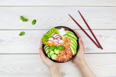 Somon, pirinç, turp, havuç, salatalık. Bir kadının elinde Hawaii ahi 'si. Balıklı diyet yemeği.. 