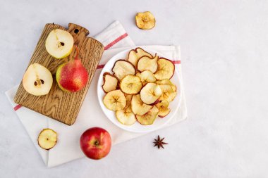 Homemade dried sliced apple and pear on a plate on a light gray background. Fruit chips. Vegan dessert sugar free. 