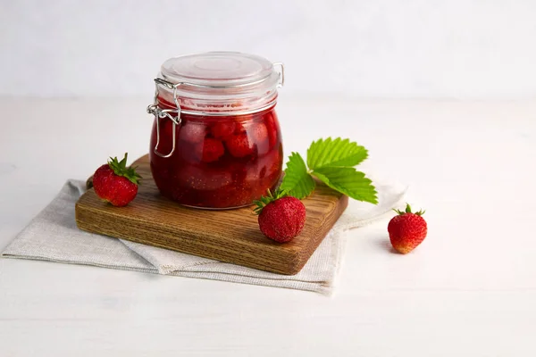 Strawberry jam in a glass jar with fresh berries on white wooden background. Homemade strawberry marmelade. — Stock Photo, Image