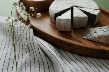 Ahşap oval tabakta dilimlenmiş küflenmiş peynir. Kaba camembert peyniri. Güzel bir yemek servisi..