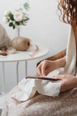 Bir kadının elleri keten kumaşa işlenir. Bir kadın işlemeli bir çerçeve ve nakış taşır..