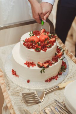 Olgun böğürtlenlerle süslenmiş, bıçakla kesilmiş düğün pastası. Düğün yemeği..
