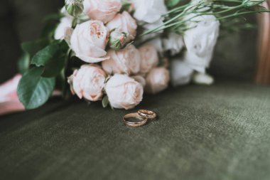 Yeşil arka planda düğün buketi ve yüzükler. Düğün hazırlıkları.