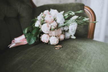 Düğün buketi ve yeşil bir koltukta yüzükler. Düğün hazırlıkları.
