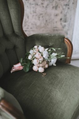 Düğün buketi ve yeşil bir koltukta yüzükler. Düğün hazırlıkları.