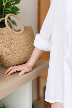 Beyaz gömlekli bir kız masanın yanında duruyor. Eller yukarı. Beyaz gömlek