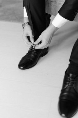 Adam siyah ayakkabıların bağcıklarını sıkıca bağlıyor. Şık ayakkabılar. Siyah beyaz fotoğraf