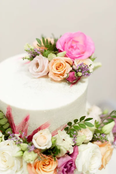 white wedding cake decorated with flowers close-up. The wedding cake