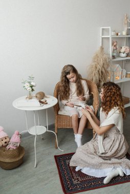 Annem küçük kızına parlak bir odada kumaş işlemeyi öğretiyor.