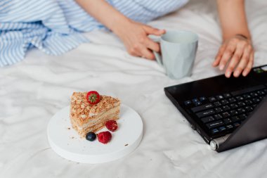 Laptop iş kahvaltısının yanındaki yatağa yakın plan güzel bir pasta.