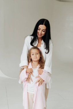 Güzel esmer anne ve kızı beyaz bir duvar arkasında