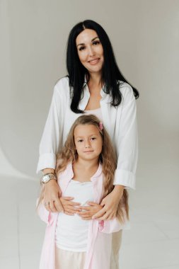 Güzel esmer anne ve kızı beyaz bir duvar arkasında