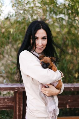 Açık renk elbiseli şirin kız küçük köpeğini kollarında tutuyor.