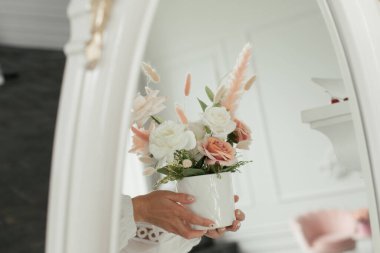 Bir kızın ellerinde bir buket suni çiçek beyaz bir aynaya yansıyor.