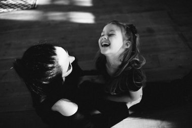 Güzel anne ve kız yerde birlikte oturuyorlar. Siyah beyaz fotoğraf.