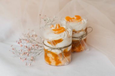 Masanın üzerinde şeffaf bir fincanda mandalinalı meyveli puding.