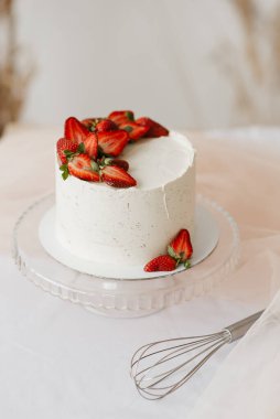 Tepside çilek ve beyaz bir masada çırpılmış tatlı beyaz kremalı pasta.