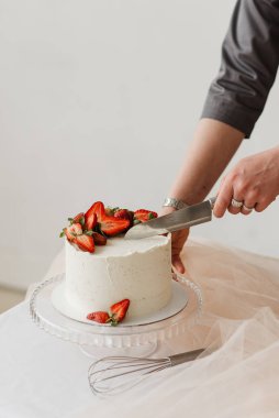 Pasta şefi, beyaz çilekli pastayı bıçakla keser.