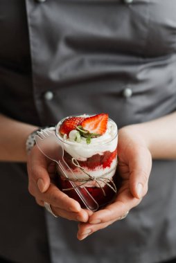 Pasta şefi kız cam bardakta puding tutuyor.