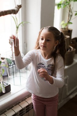 Beyaz tişörtlü, elinde bir test tüpü tutan ateşli küçük kız.