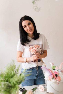 Çiçekçi bir buket çiçek toplar. Çiçekli beyaz tişörtlü güzel esmer kız.