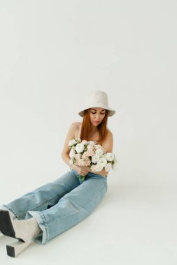 Stüdyoda bej bir arka planda fotoğraf. Mavi kot içinde güzel bir model.