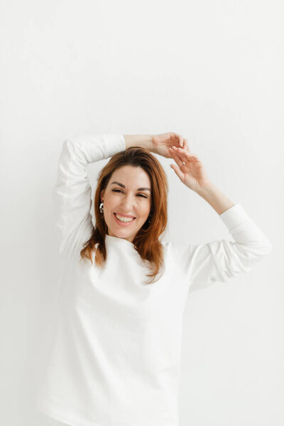 красивая девушка в белом свитере держит руки над головой