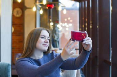 Kafede cep telefonuyla selfie çeken genç kadınlar.