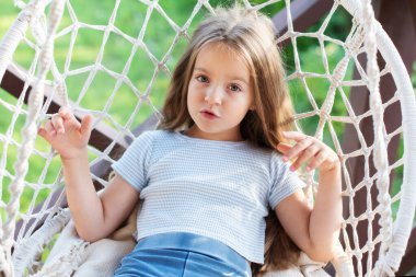 Kafkasyalı genç kız dışarıda, hamak sandalyesinde dinleniyor..