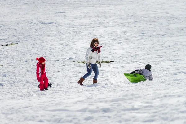 Mamma med barn pulka på snow hill — Stockfoto