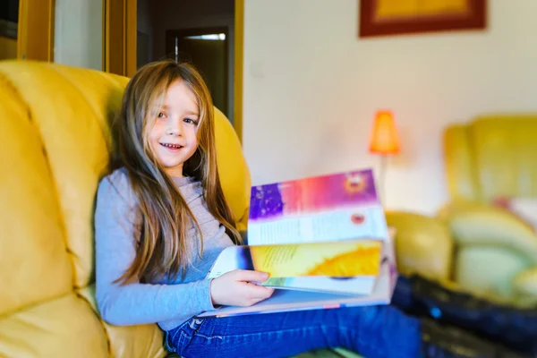 Menina bonito com cabelo longo leitura crianças livro na livivng — Fotografia de Stock