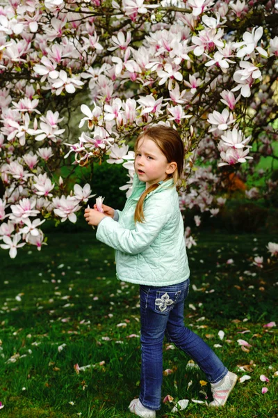 Preschooler dívka si hraje s květy magnólie — Stock fotografie