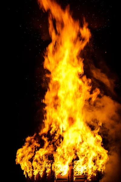 Techo de casa de madera en el fuego sobre fondo negro —  Fotos de Stock