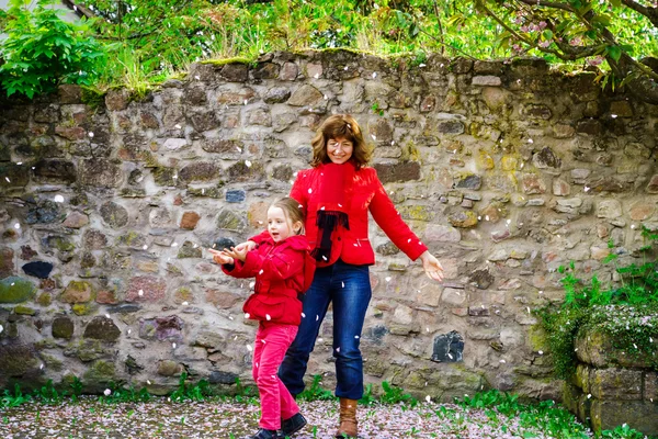 Mère avec petite fille jouant avec des pétales tombants printemps d — Photo