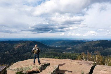 Bir adam uçurumun tepesinde duran bir dronu kontrol eder. Sonbahar dağ manzarası. Vosges, Alsace. Fransa
