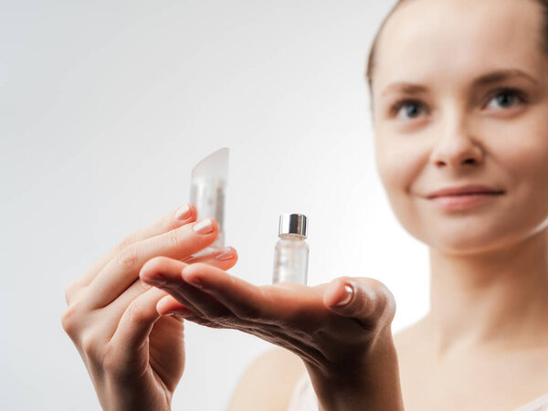 Beautiful Young Woman with Clean Fresh Skin showing the product for skin care. Girl beauty face care. Facial treatment . Cosmetology , beauty and spa. Natural cosmetic product. Concept of Organic, Bio Cosmetics. Isolated on white background.